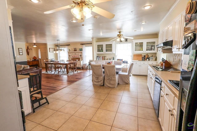 kitchen with glass insert cabinets, under cabinet range hood, light tile patterned floors, white cabinets, and black appliances