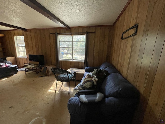 living area with beam ceiling, wooden walls, a healthy amount of sunlight, and a textured ceiling