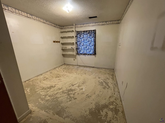 spare room with a textured ceiling and concrete flooring