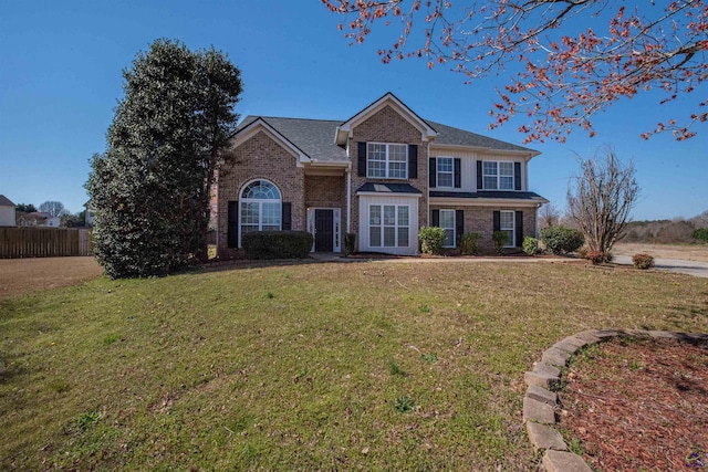 traditional home featuring brick siding, a shingled roof, a front yard, and fence