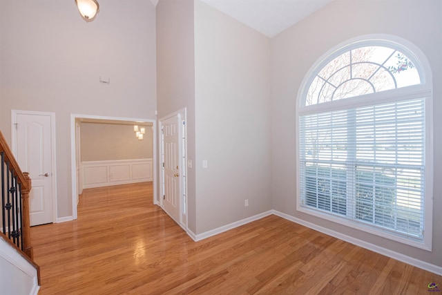 interior space featuring light wood-style flooring, baseboards, stairs, and a high ceiling