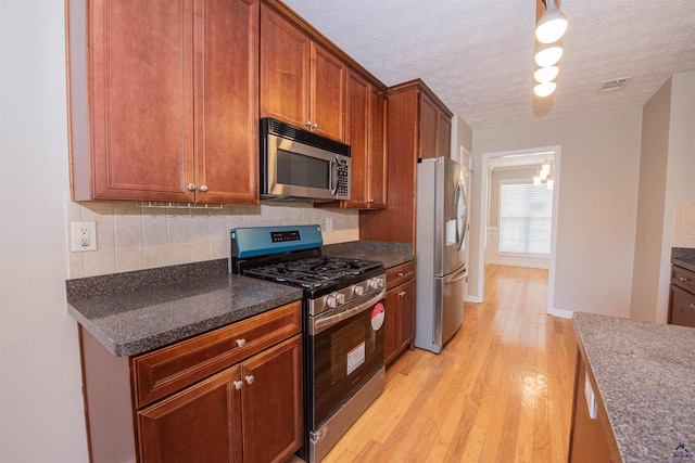 kitchen with visible vents, light wood-style flooring, tasteful backsplash, a textured ceiling, and appliances with stainless steel finishes