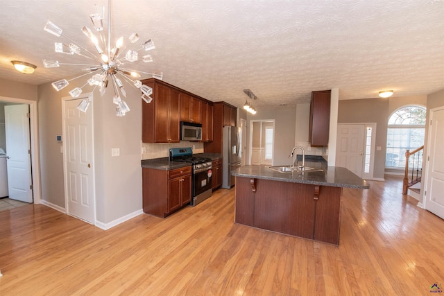 kitchen with light wood finished floors, a breakfast bar area, a notable chandelier, stainless steel appliances, and a sink