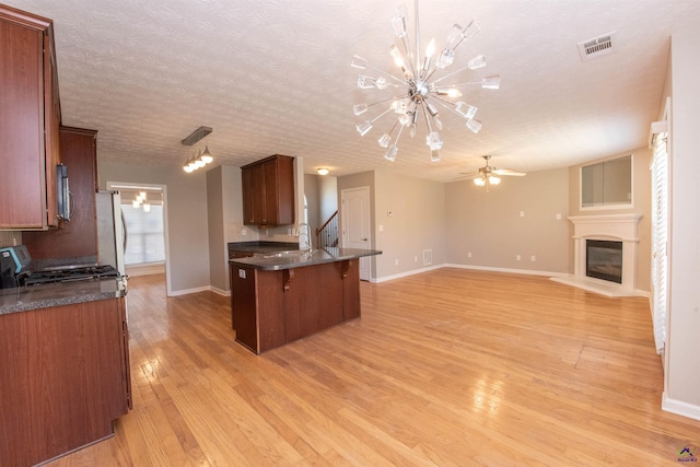 kitchen featuring visible vents, a breakfast bar, stainless steel microwave, open floor plan, and range with gas cooktop