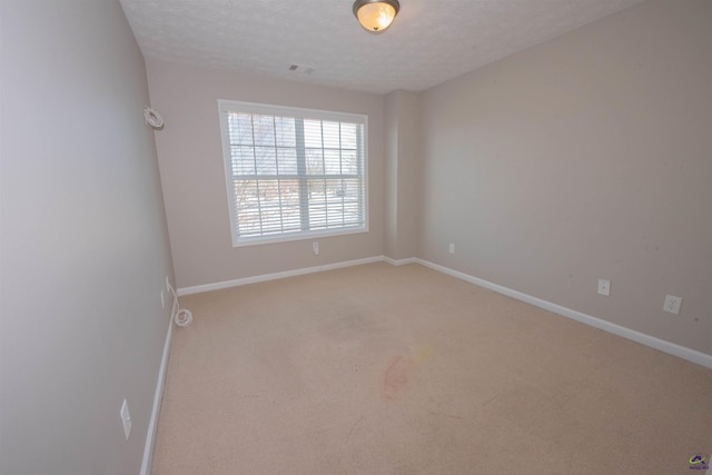 unfurnished room featuring visible vents, light colored carpet, baseboards, and a textured ceiling