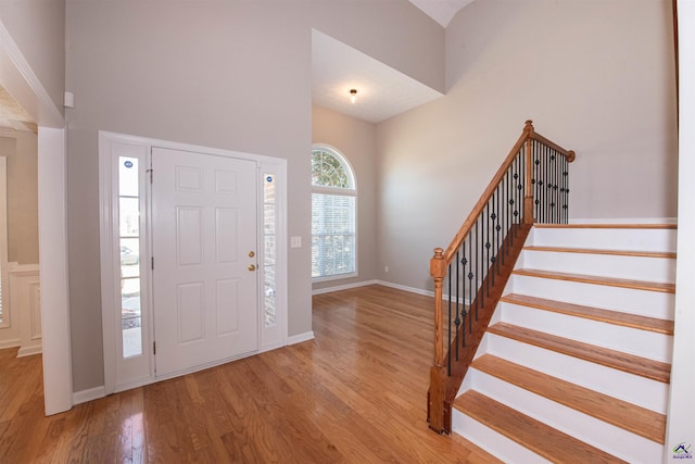 entryway featuring stairway, baseboards, a high ceiling, and wood finished floors