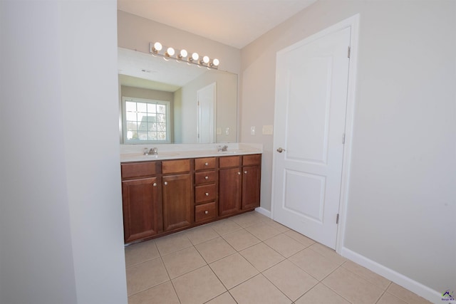 bathroom with tile patterned flooring, double vanity, baseboards, and a sink