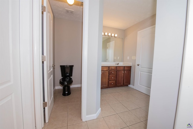 bathroom featuring vanity, baseboards, visible vents, tile patterned flooring, and a textured ceiling