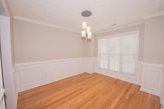 spare room with visible vents, light wood-style floors, an inviting chandelier, and crown molding