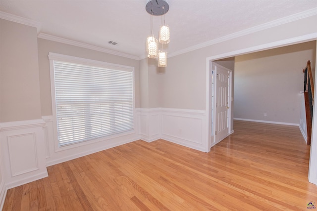 unfurnished room featuring visible vents, crown molding, a chandelier, a wainscoted wall, and light wood-style floors