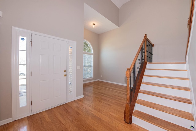 foyer entrance featuring stairs, vaulted ceiling, wood finished floors, and baseboards