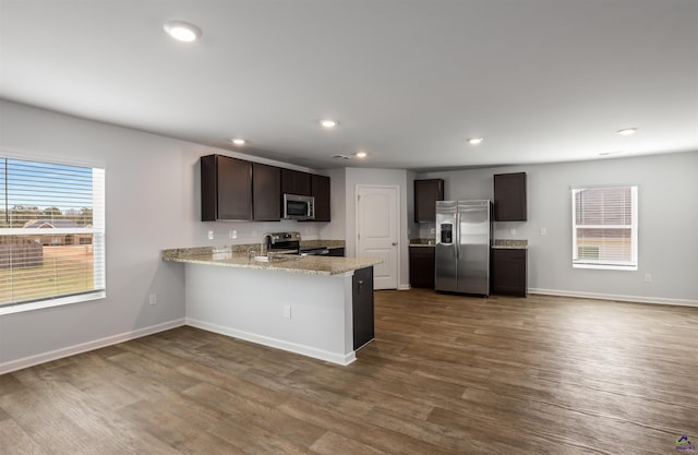 kitchen with baseboards, dark wood finished floors, a peninsula, recessed lighting, and appliances with stainless steel finishes