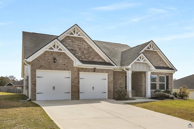 craftsman-style home featuring brick siding, an attached garage, a shingled roof, a front lawn, and driveway