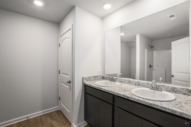 bathroom featuring double vanity, wood finished floors, baseboards, and a sink