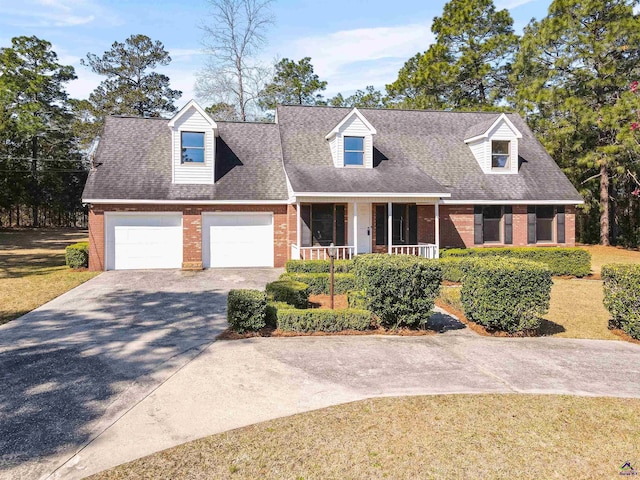 cape cod house with driveway, a porch, a shingled roof, a garage, and brick siding