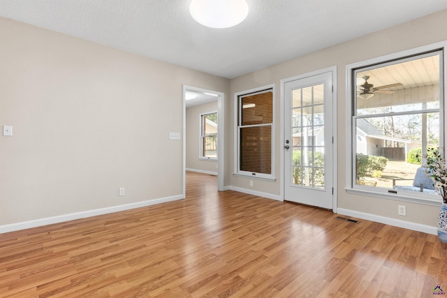 interior space with visible vents, a healthy amount of sunlight, light wood-type flooring, and baseboards