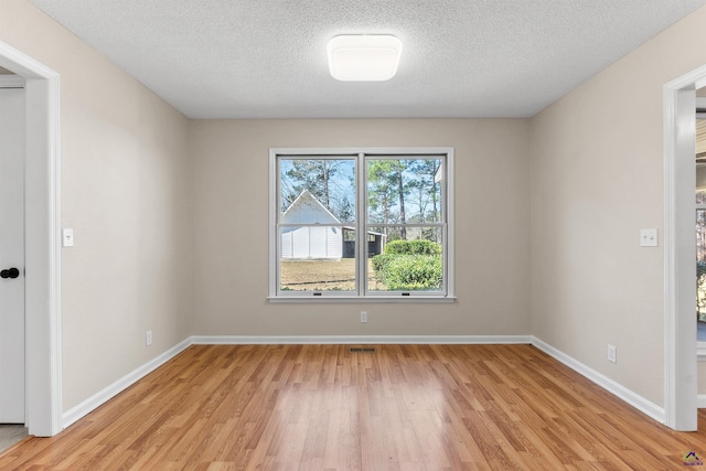 unfurnished room featuring visible vents, baseboards, a textured ceiling, and light wood-style flooring