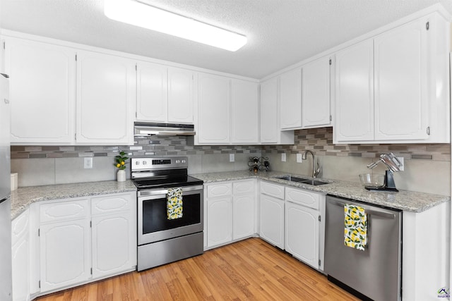 kitchen featuring under cabinet range hood, stainless steel appliances, light wood-style floors, white cabinetry, and a sink