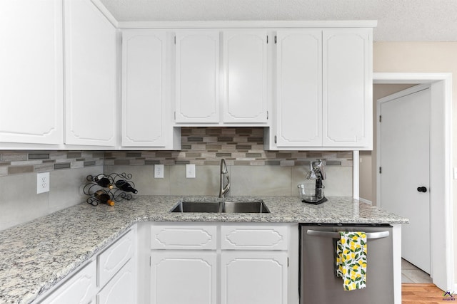 kitchen with a sink, decorative backsplash, stainless steel dishwasher, and white cabinetry