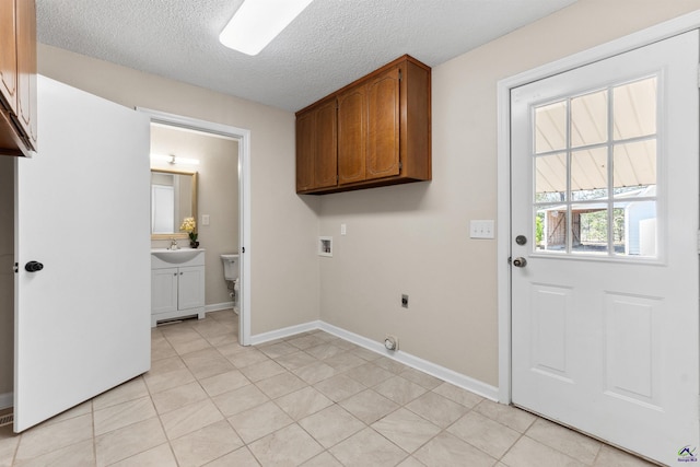 clothes washing area featuring baseboards, washer hookup, electric dryer hookup, a textured ceiling, and a sink