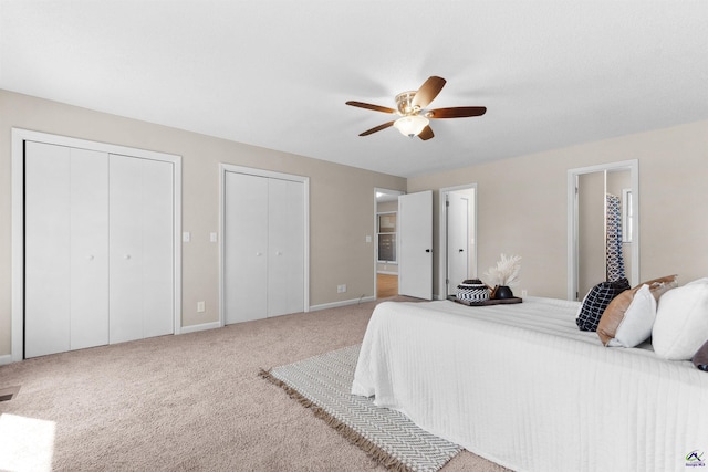 bedroom with connected bathroom, two closets, baseboards, carpet floors, and a ceiling fan