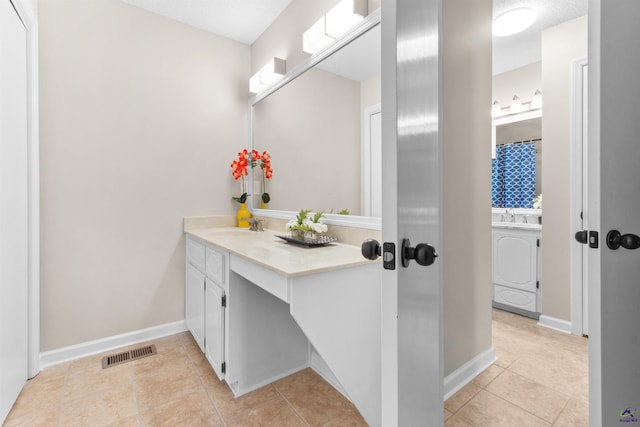 bathroom featuring tile patterned floors, visible vents, baseboards, washer / dryer, and vanity