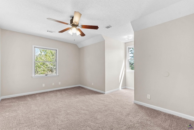 carpeted spare room with a wealth of natural light, visible vents, baseboards, and a ceiling fan