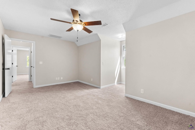 carpeted spare room with visible vents, a textured ceiling, and baseboards