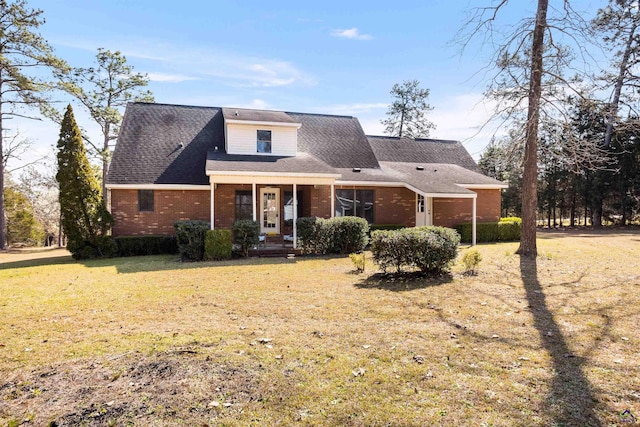 traditional home featuring brick siding, a front yard, and a shingled roof