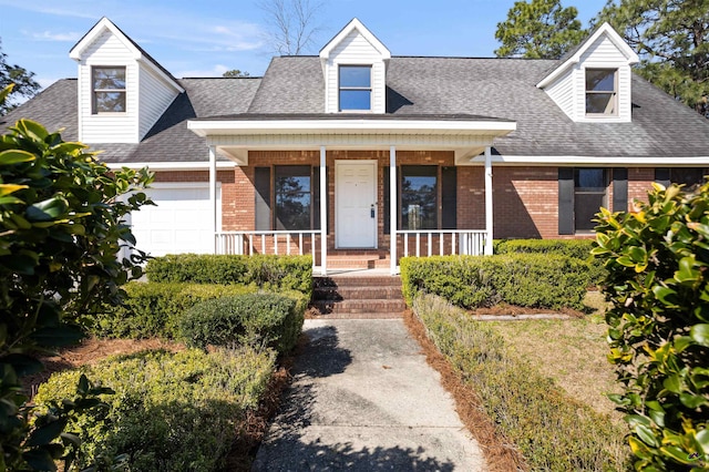 new england style home with brick siding, covered porch, an attached garage, and a shingled roof