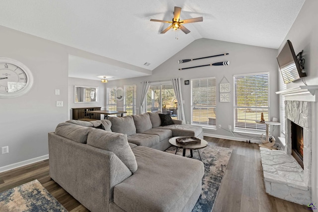 living room featuring baseboards, a premium fireplace, dark wood finished floors, lofted ceiling, and ceiling fan