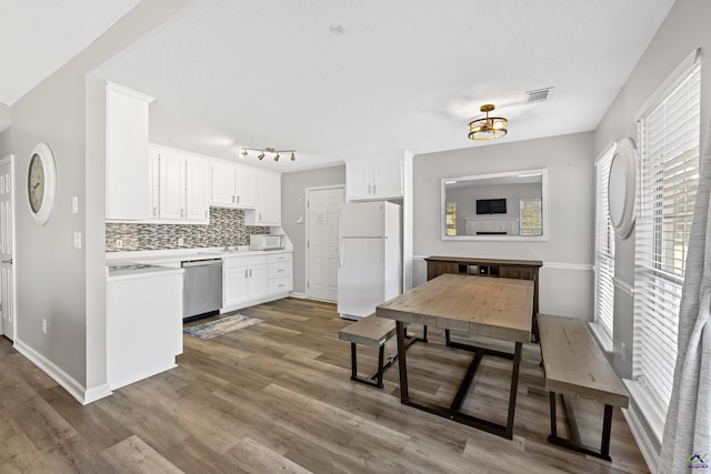 kitchen with visible vents, tasteful backsplash, dark wood-style floors, white cabinetry, and white appliances