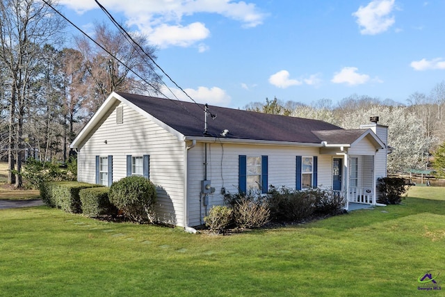 view of side of property with a chimney and a yard