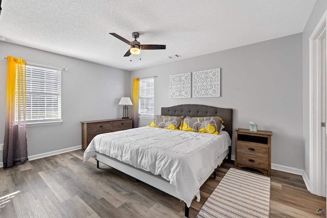 bedroom featuring visible vents, multiple windows, baseboards, and wood finished floors