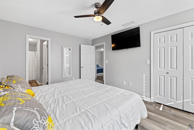 bedroom featuring visible vents, a textured ceiling, wood finished floors, a closet, and ceiling fan