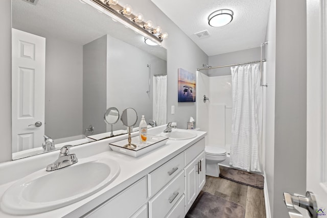 full bath with a sink, toilet, wood finished floors, and a textured ceiling