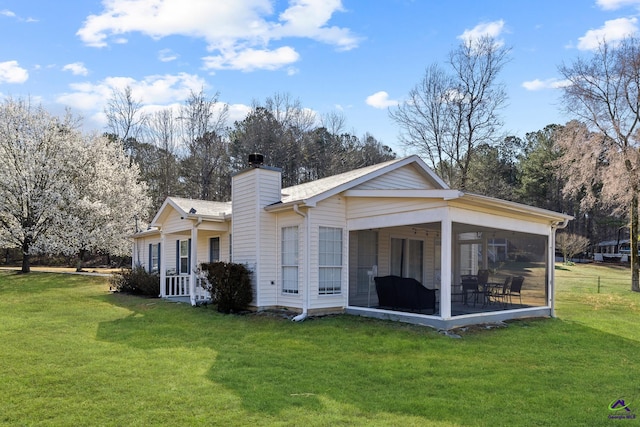 back of property featuring a yard, a sunroom, and a chimney