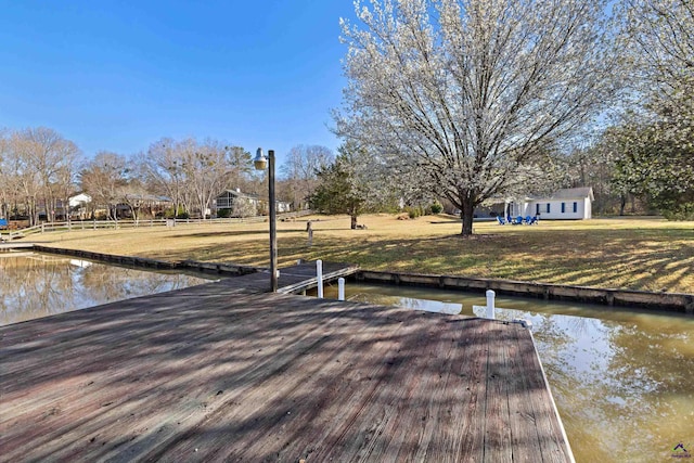 view of dock featuring a water view and a lawn