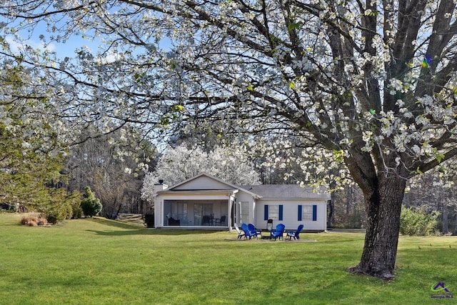 back of property featuring a yard, a sunroom, and a chimney