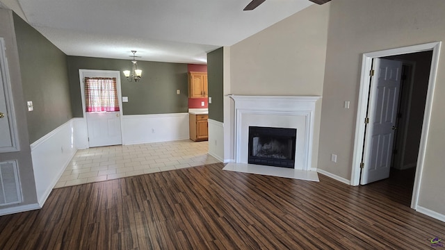 unfurnished living room with a wainscoted wall, wood finished floors, a fireplace, and visible vents