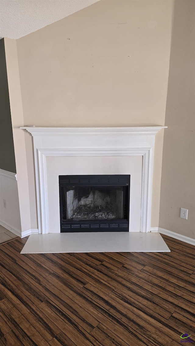 room details with baseboards, wood finished floors, and a fireplace with raised hearth