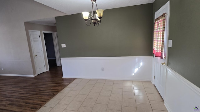 spare room featuring an inviting chandelier, wood finished floors, and lofted ceiling