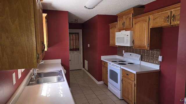 kitchen featuring a sink, tasteful backsplash, white appliances, light countertops, and light tile patterned floors