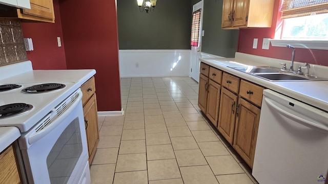 kitchen with light countertops, light tile patterned floors, brown cabinetry, white appliances, and a sink