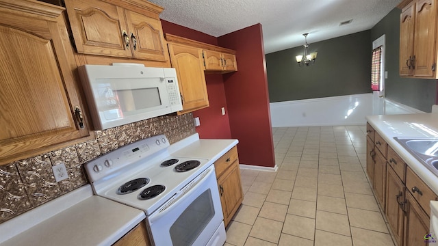 kitchen with light tile patterned floors, white appliances, a chandelier, and light countertops