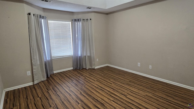 unfurnished room with visible vents, a textured ceiling, baseboards, and wood finished floors