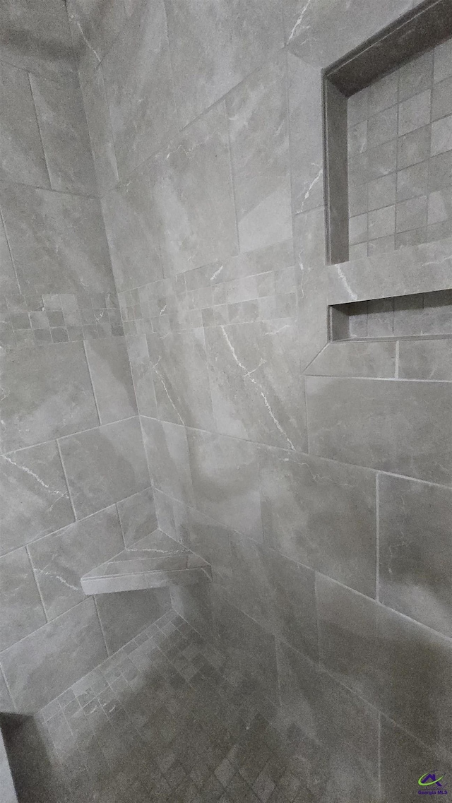 interior details featuring tiled shower