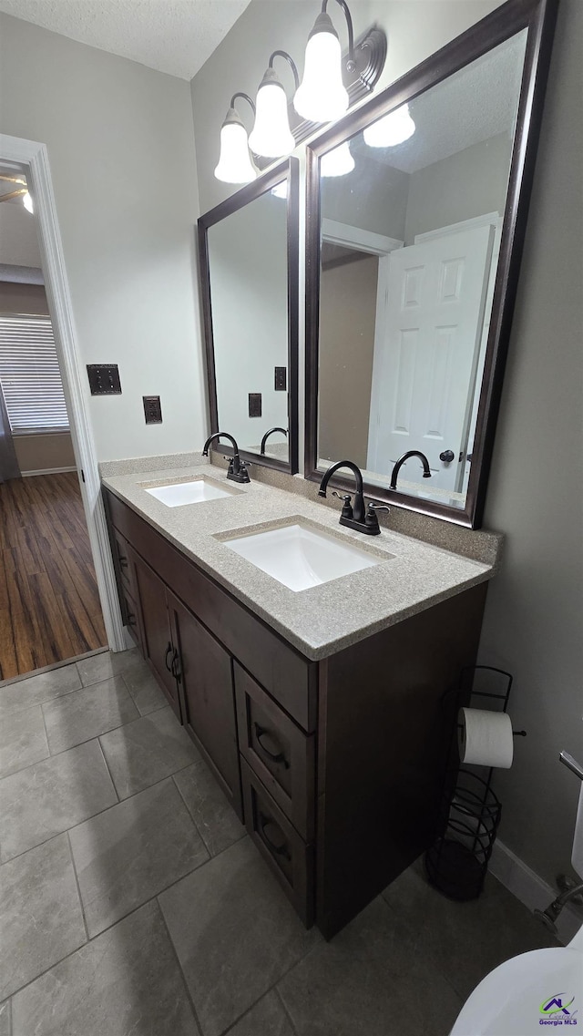 bathroom with double vanity, tile patterned flooring, a textured ceiling, and a sink