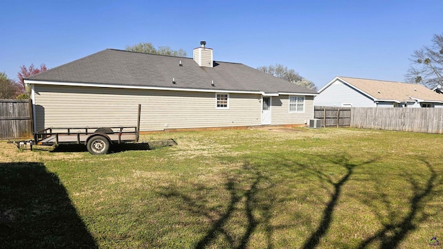 back of property featuring a fenced backyard, cooling unit, a chimney, and a yard