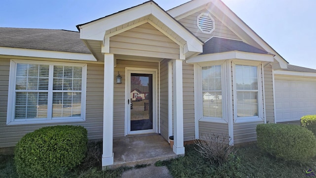 entrance to property with a shingled roof and a garage